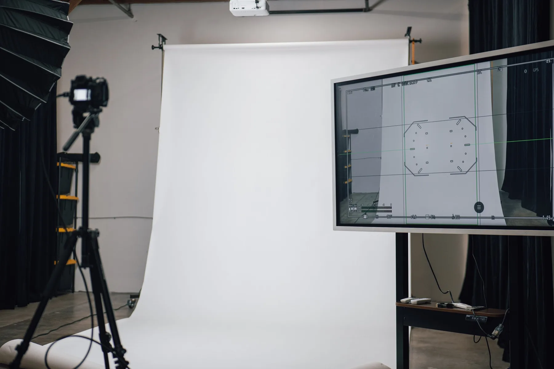 Camera and production monitor facing a white seamless backdrop
