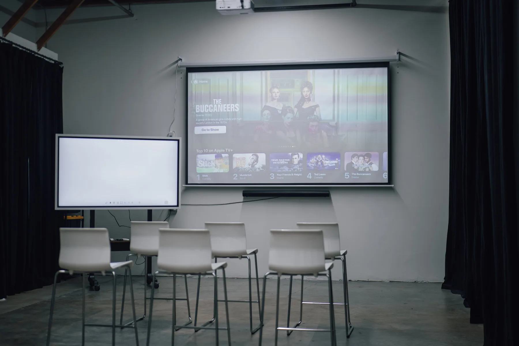Studio 591 configured with chairs, a projector screen and presentation monitor